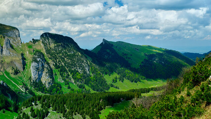 Breathtaking mountain landscape with green hills and dramatic clouds in Switzerland during daytime