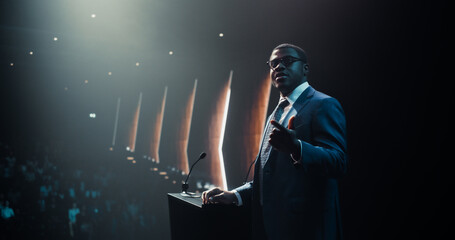 Energetic Speaker Giving a Speech at a Modern Conference Hall in Front of Crowd of Corporate...