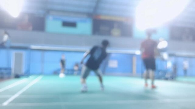Blurred environment view of a badminton gym while people play and learn the indoor game.	