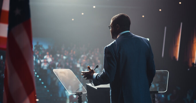Political Speaker at a Government Election Rally. Black Male Candidate Waving to Supporters, Walking Towards the Tribune Stand to Deliver a Motivational Speech About Equality, Integrity and Freedom - Powered by Adobe