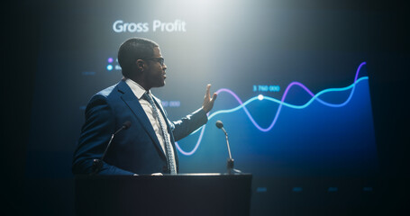 Businessman Giving a Talk at a Global Finance Summit. Audience Listening to His Insightful Talk. Speaker Showing a Presentation on Screen While Making a Motivational Speech