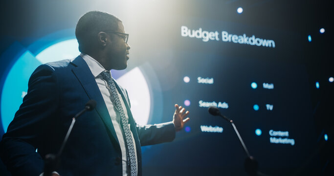 Handsome African Speaker with Expertise in Technology, Finance, Business, and Politics, Coaching a Diverse Group of Young Specialists During a Presentation at a Strategic Growth Conference