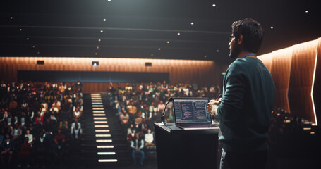 South Asian Software Developer Using Laptop Computer and Delivering a Motivational Speech on Stage, Hosting a Seminar to Help Entrepreneurs Overcome Their Personal and Professional Challenges