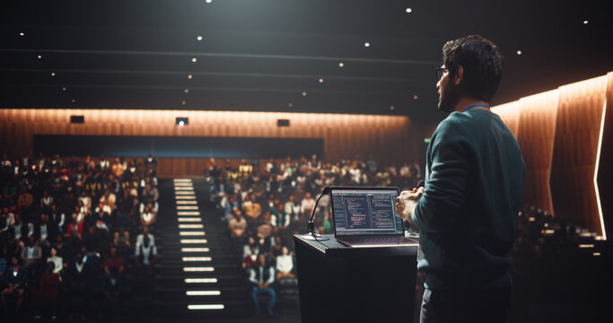South Asian Software Developer Using Laptop Computer and Delivering a Motivational Speech on Stage, Hosting a Seminar to Help Entrepreneurs Overcome Their Personal and Professional Challenges