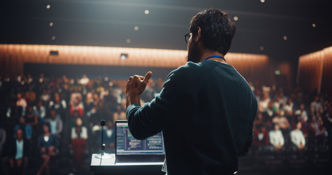 Indian Business Leader Giving a Talk on Stage at a Global Finance Summit. Audience Listening to an Insightful Talk. Speaker Standing with a Microphone and Making a Motivational Speech