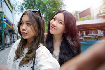 Two Young Asian Women Taking a Selfie Together on a Fun Day Out in the City