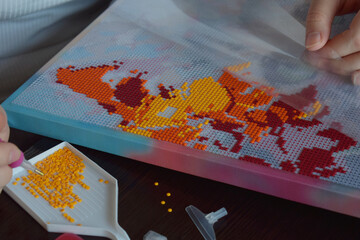 Hands working on diamond painting placing colorful beads on a canvas creating an artistic vibrant mosaic perfect for DIY crafting hobbies and creative handmade art concepts
