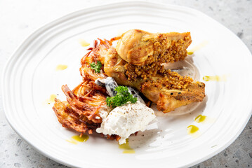 Gourmet dish with roasted chicken breast topped with mustard seeds, served alongside crispy potato rosti, sour cream, and garnished with fresh parsley on a white plate.