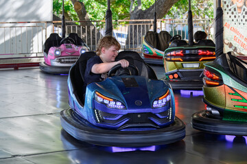 Teenage boy in dodgem bumper car, fun in sideshow alley, fun fair, amusement ride © Cynthia