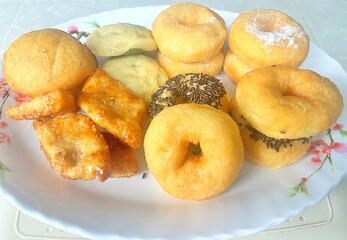 A plate of assorted traditional fried snacks, including mini donuts, fried pastries, and cookies. These homemade treats are commonly served as breakfast or afternoon snacks in Southeast Asia.