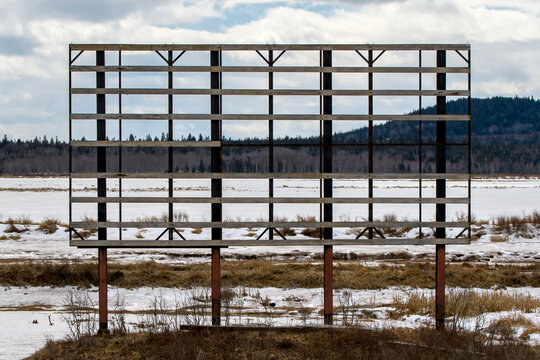 A large billboard in winter, with the advertisement completely blown away. Only the frame remains.