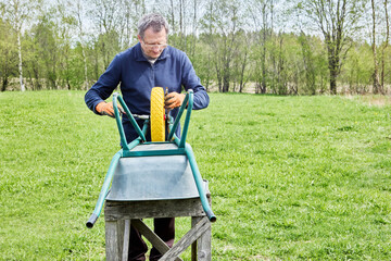 Farm worker fitting solid polyurethane wheel onto utility cart to ensure smooth operation and...