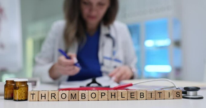 Word Thrombophlebitis of wooden blocks against healthcare worker in clinic. Woman reviews patient records examining symptoms in hospital environment