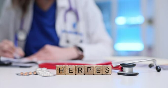 Text Herpes of wood blocks near pills blisters and stethoscope on doctor desk. Female physician documents patient diagnose in dermatological clinic