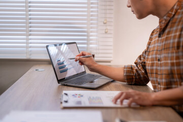 A man is sitting at a desk with a laptop and a clipboard
