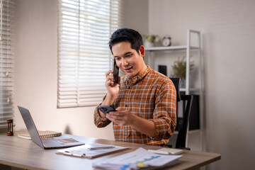 A man is talking on his cell phone while sitting at a desk
