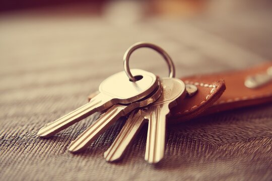 Close-Up of Multiple Metal Keys on a Brown Leather Keychain, Showcasing the Texture and Detail of the Keys Against a Soft Background