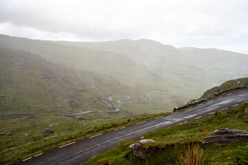 Fototapeta premium Gewundene Straße durch die raue Berglandschaft Irlands Healy Pass in der grünen Berglandschaft Irlands