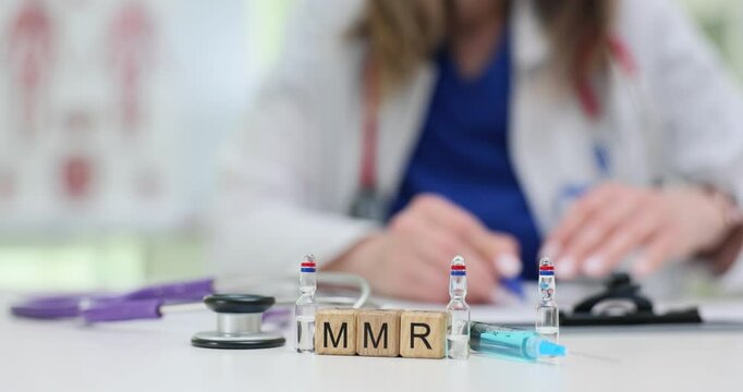 Woman writes on documents against MMR vaccine vials and syringe on desk. Importance of measles mumps and rubella vaccination for children health