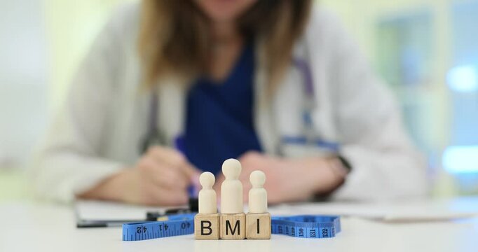 Female professional evaluates BMI near wooden figurines depicting weight management challenges. Healthcare assessment and obesity concerns at hospital