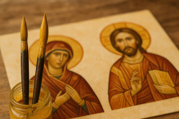 Obraz premium Religious icon painting with brushes and tempera paint, depicting jesus christ and virgin mary in traditional byzantine