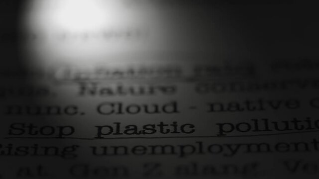 Stop plastic pollution. Topic of environmental conservation. Moving text printed on a page. Headline. A piece of paper with a phrase written in retro typewriter font. Spotlight effect. Dramatic video.