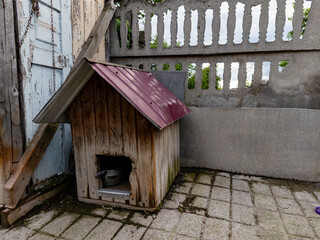 A dog house with a metal roof next to a fence