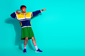 Young athlete in vibrant retro sportswear posing dynamically on a bright teal background, showcasing vintage style, activewear fashion