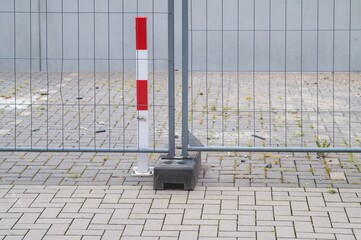 Red and white pole securing mobile fence on construction site