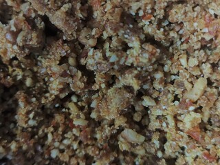 A macro photo of mixed nuts and ingredients in a textured food cluster.