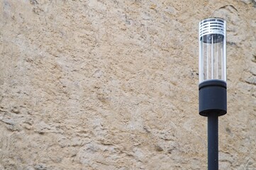 Modern street lamp standing next to an old stone wall