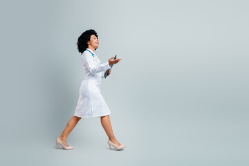 Young female doctor walking confidently with a clipboard, expressing professionalism and dedication...