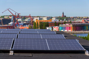 Solar panels on roof of apartment housing building with Gothenburg city center in background, Sweden, renewable green sustainable energy concept