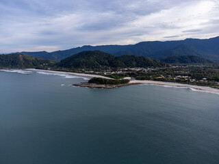 Beautiful coastal village on a beach with green waters and orange sand amidst the mountains