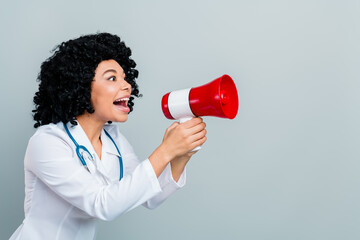 Female doctor joyfully speaking through a megaphone, wearing white coat and stethoscope
