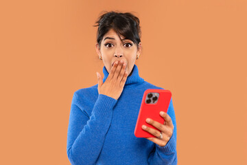 Surprised woman reacts while using her smartphone in cozy indoor setting during day