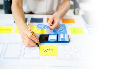 Creative UX UI designer working on app wireframe layout with sticky notes and color palette. web...