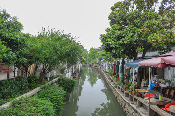 Fototapeta premium Green Riverside Boats And Charming Shops Along Historic Suzhou Nanjing Grand Canal