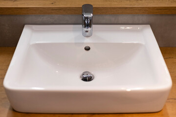 A stylish bathroom sink features a smooth, rectangular design, complemented by a polished faucet. The sink is set on a natural wood countertop, creating a contemporary look and simple elegance