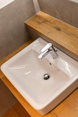 This bathroom features a compact modern sink with a sleek chrome faucet set against a wooden countertop. The minimalist design complements the contemporary aesthetic of the space