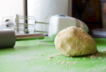 Preparing shortcrust pastry for baking tarts. Mixer and rolling pin in the background. Young woman's hands preparing dough for desserts.