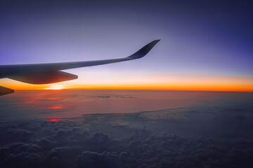 Fototapeta premium Sunrise Above The Sea Of Clouds From Airplane Window At Dawn In Atmospheric Flight