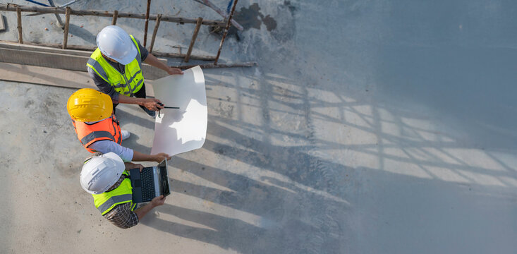Three Asian engineer working at site of a large building project,Work overtime at construction site,Team of engineer discus at site,The architect, supervisor, and foreman meet to discuss the design
