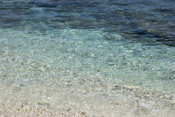 Clear blue sea water and white sand. Light sand under the clear water. Clear blue sea. Turquoise sea water of Crete island in Greece. Sea surface
