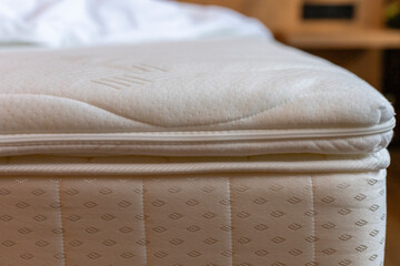 A padded mattress is positioned on a wooden bed frame, featuring a smooth, soft top layer. The cozy...