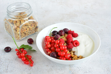 Healthy Breakfast Bowl with Granola, Berries and Yogurt and a jar with oat flakes