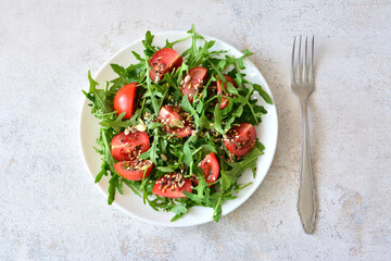 Fresh Arugula and Tomato Salad with Seeds and a fork top view