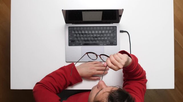 top view Tired programmer removing glasses after working on laptop all day long