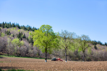 farmer harrows land near clervaux in luxemburg