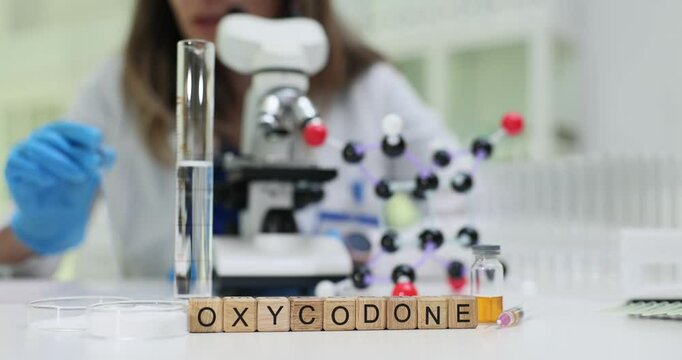 Laboratory technician analyzes Oxycodone with microscope near molecular model. Research and development for pain management in modern clinic